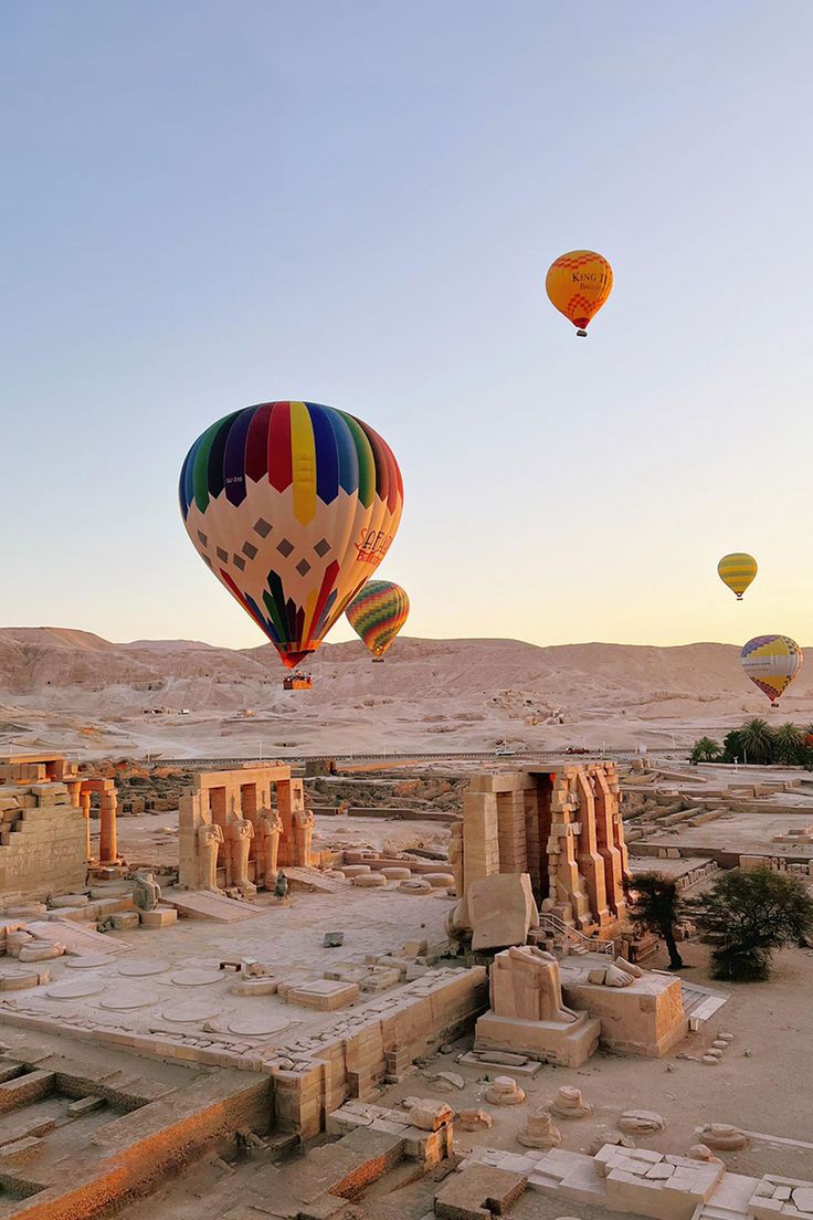 Hot air balloons flying over Luxor temples and the Nile at sunrise.