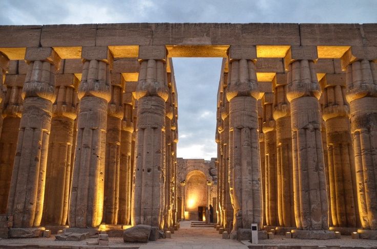 Luxor Temple illuminated at night with reflection on the Nile River.